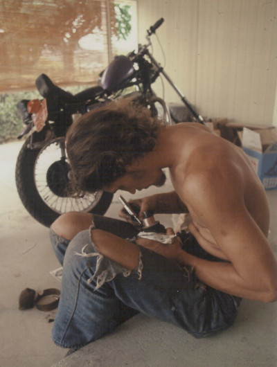 Dako working on his armature, 1972, with a friend's crazy Triumph bobbler in the background.